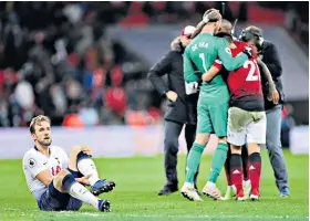  ??  ?? Pain game: Harry Kane clutches his ankle as United players celebrate their win