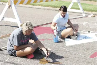  ?? Brodie Johnson • Times-Herald ?? St. Francis County Farm Bureau employees Holly Loewer, left, and Candice Kelso help paint a crosswalk at the intersecti­on of Dillard and Rosser streets this morning. Groups have painted several crosswalks in the downtown area as part of an ArDROP project.