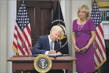  ?? Pablo Martinez Monsivais Associated Press ?? PRESIDENT BIDEN, with First Lady Jill Biden, signs a bipartisan bill Saturday that, among other things, will toughen background checks for the youngest gun buyers and help states establish “red f lag” laws.