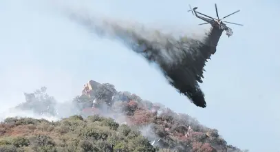  ?? Picture: EPA ?? DOUSED. A helicopter drops water on brush burning near Pepperdine University as the Woolsey Fire continues to burn in Malibu, California. Fires are fuelled by dry conditions and strong Santa Ana winds.