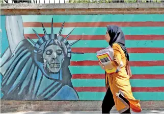  ??  ?? A woman walks past a mural painting along the wall of the former US embassy in the Iranian capital Tehran on June 22, 2019. (Photo by ATTA KENARE / AFP)