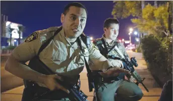  ?? AP PHOTO ?? Police officers advise people to take cover near the scene of a shooting near the Mandalay Bay resort and casino on the Las Vegas Strip.