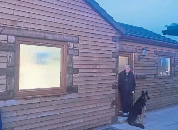  ??  ?? Marion Cook lives in a specially-built log cabin in her daughter’s garden, allowing her to access care and visits from her loved ones – including Jacko the German shepherd – while still having her own home.