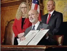  ?? ASSOCIATED PRESS ?? Gov. Tom Wolf shows the document he signed declaring a state of emergency in the state’s fight against heroin and opioid addiction during a news conference at the state Capitol in Harrisburg on Wednesday. In the background are Acting Secretary of...