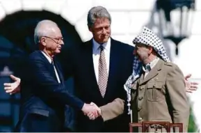  ?? REUTERS PIC ?? Former Israeli prime minister Yitzhak Rabin (left) shaking hands with PLO chairman Yasser Arafat, with former US president Bill Clinton as the host, at the White House after the signing of the Oslo Accords on Sept 13, 1993.