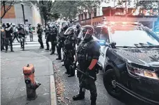  ?? /EFE ?? Miembros de la policía de Portland montan guardia afuera del Centro de Justicia durante las protestas de BLM.