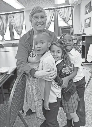  ?? PROVIDED BY ST. CLARE OF MONTEFALCO CATHOLIC SCHOOL ?? Sister Kathy Avery, 80, former principal at St. Clare of Montefalco Catholic School in Grosse Pointe Park, embraces three students at the start of the 2023 school year. She is leaving St. Clare after 16 years of service and moving back to her motherhous­e in Omaha, Neb.