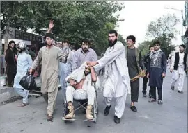  ?? Wakil Kohsar AFP/Getty Images ?? A WOUNDED MAN is pushed in a wheelchair after a series of explosions targeted the funeral of a politician’s son. More than 100 people were injured.