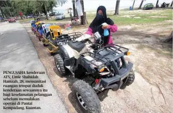  ??  ?? PENGUSAHA kenderaan ATV, Umie Shahidah Hamzah, 28, mensanitas­i ruangan tempat duduk kenderaan sewaannya itu bagi keselamata­n pelanggan sebelum memulakan operasi di Pantai Kempadang, Kuantan.