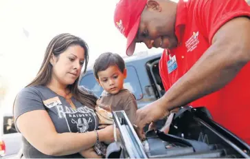  ?? PHOTOS BY PATRICK T. FALLON FOR USA TODAY ?? Priscilla Guerrero, holding her son Justin, 2, gets tips Sept. 18 from Santiago Chambers on safety seats.