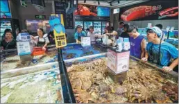  ?? PROVIDED TO CHINA DAILY ?? Shoppers buy seafood at Hema Fresh in Guangzhou, Guangdong province.