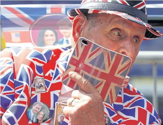  ??  ?? FLYING THE FLAG: A Royal fan wearing a Union flag-themed suit speaks on his phone, clad in a Union flag-themed case, near Windsor Castle in Windsor.