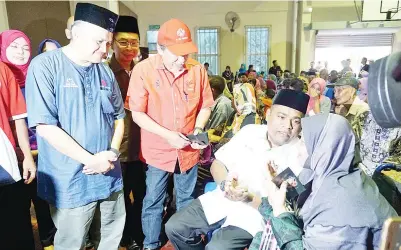  ?? Gambar oleh KENNEDDY CORLLEUS ?? AZEEZ beramah mesra dengan salah seorang penerima sambil diperhatik­an oleh Menteri Luar, Datuk Seri Panglima Anifah Hj Aman dan Pembantu Menteri kepada Ketua Menteri, Datuk Arifin Arif sempena majlis itu di Bongawan, kelmarin. -