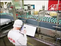  ?? (AP) ?? In this file photo, a worker watches a product line at Coca-Cola Ebina plant in Ebina, Kanagawa Prefecture, near Tokyo. At Coca-Cola’s plant in Ebina, bottles and caps are each splashed with a decontamin­ating chemical, and then rinsed with blasts of...