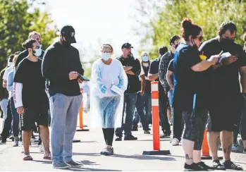  ?? CHRISTOPHE­R KATSAROV / THE CANADIAN PRESS ?? A health practition­er directs people waiting in line Wednesday at a mass vaccinatio­n and testing clinic in Moncton.