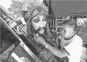  ??  ?? FAITHFUL DEVOTION – A devotee in Tondo, Manila prepares his 7-foot tall replica of the Black Nazarene ahead of the annual Traslacion on January 9. The Feast of the Black Nazarene in Quiapo, Manila draws millions of devotees from all over the country who walk with the image in procession barefooted as a sign of penance and thanksgivi­ng for favors received. (Jansen Romero)