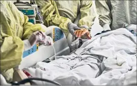  ?? GINA FERAZZI Los Angeles Times ?? A NURSE holds a patient’s hand Tuesday at Loma Linda University Medical Center. Health off icials say holiday gatherings will only worsen the virus’ surge.