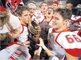  ??  ?? Carl Albert celebrates with the trophy Friday after the Class 5A state championsh­ip football game against Bishop McGuinness in Yukon.