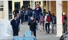  ?? DAVID JOLES / (MINNEAPOLI­S) STAR TRIBUNE ?? Police officers stand guard as Orono High School students in Orono, Minn., arrive for school Feb. 22, one day after a threat was posted, causing the school to go on lockdown. An autistic student at the school was being detained in the case.