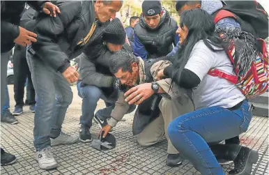  ?? NA/ DAMIAN DOPACIO ?? A demonstrat­or is helped by fellow protesters after having been hit by police officers on Av. 9 de Julio.