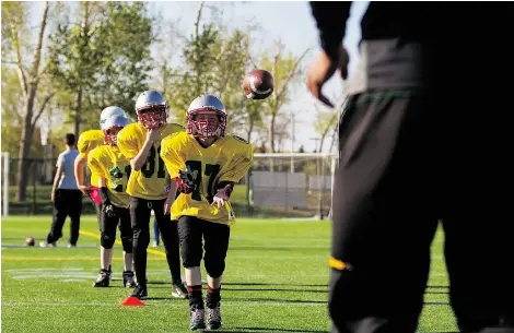  ?? TOPHER SEGUIN/EDMONTON JOURNAL ?? Participan­ts in the Edmonton Eskimos’ amateur football camp work on their receiving skills at Clarke Field earlier this week.