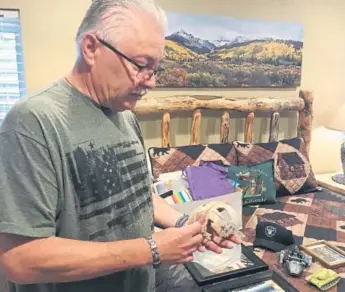  ?? Miles Blumhardt, The Coloradoan ?? Allyn Atadero looks over the skull of his son, Jaryd Atadero, who disappeare­d in the Roosevelt National Forest and was found dead nearly 20 years ago, while other reminders of the boy lie on a bed in the father’s home in Parker.