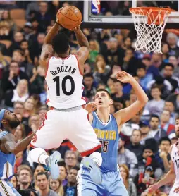  ?? (Reuters) ?? TORONTO RAPTORS guard DeMar DeRozan takes a jump shot over Denver Nuggets center Nikola Jokic (15) for two of his game-high 33 points in the Raptors’ 105-102 home victory on Monday night.