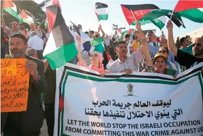  ?? — AfP ?? Palestinia­ns wave their national flag as they demonstrat­e in support of Bedouin inhabitant­s near their village of Khan Al Ahmar, in the occupied west Bank. Israel claims the Bedouin village was constructe­d illegally and is seeking to move its residents elsewhere.