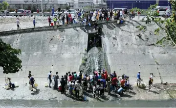  ??  ?? People collect water from a sewage canal at the river Guaire in Caracas as a massive power outage continues affecting some areas of the country.