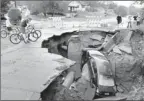  ?? By Brian Peterson The (Minneapoli­s) Star Tribune via AP ?? In Duluth, Minn.: A car sits in a giant sinkhole on Wednesday after a storm forced evacuation­s.