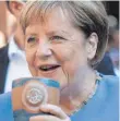  ?? FOTO: DPA ?? Angela Merkel trinkt bei der Stralsunde­r Stadtwache ein Bier.