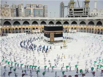  ??  ?? Limited numbers of pilgrims in Mecca move several feet apart, circling the cube-shaped Kaaba in the first rituals of the hajj, as they social-distance to help prevent the spread of the coronaviru­s.