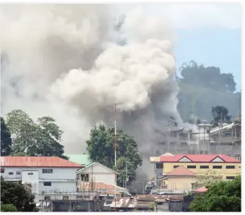  ??  ?? A June 26 file photo shows smoke billowing from a building following a bombing run against militant positions by a Philippine­s Air Force FA-50 fighter aircraft in Marawi on the southern island of Mindanao. (AFP)