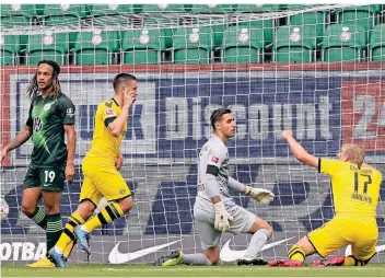  ?? FOTO: MICHAEL SOHN/AP ?? Borussia Dortmunds Raphaël Guerreiro (2. von links) feiert sein Tor zum 1:0 gegen den VfL Wolfsburg. Auch Erling Haaland (r.) freut sich, während VfL-Keeper Koen Casteels enttäuscht auf dem Rasen kniet.