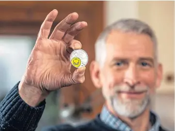  ??  ?? CHARACTERS: Adam Hargreaves holds the Royal Mint’s new £5 Mr Happy coin.