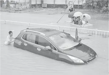  ??  ?? A trapped car is pushed along a flooded street after typhoon Soudelor hit Fuzhou, Fujian province, China.