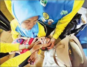  ?? THE JAKARTA POST ?? Health workers administer drops of the polio vaccine to children under 5 at an integrated health service post (Posyandu) Jati 2 in Gunung Kelurahan, Kebayoran Baru, South Jakarta, Indonesia, on March 8, 2016.
