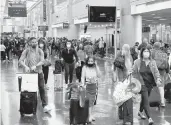  ?? DANIEL SLIM/GETTY-AFP ?? Travelers on Christmas Eve make their way through Miami Internatio­nal Airport.