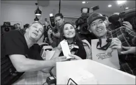  ?? PAUL DALY/THE CANADIAN PRESS VIA AP ?? CANOPY GROWTH CEO BRUCE LINTON (LEFT TO RIGHT) poses with the receipt for the first legal cannabis for recreation use sold in Canada to Nikki Rose and Ian Power at the Tweed shop on Water Street in St. John’s N.L. at 12:01 am NDT on Wednesday.