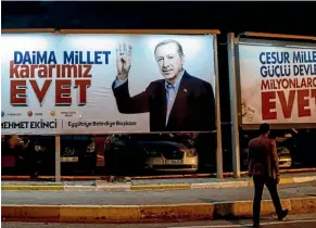  ??  ?? A man walks past an Evet" (Yes) campaign poster showing the portrait of Turkish President Recep Tayyip Erdogan in Sanliurfa, Turkey.