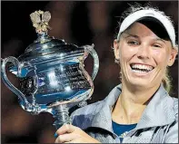  ?? AP/DITA ALANGKARA ?? Caroline Wozniacki of Denmark poses for photos with the championsh­ip trophy Saturday after defeating Simona Halep of Romania 7-6 (2), 3-6, 6-4 in the women’s singles final at the Australian Open in Melbourne, Australia.