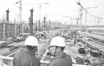  ??  ?? Workers survey a constructi­on site. Depending on the outcome of the East Coast Rail Link (ECRL) mega infrastruc­ture project, HEB may faces the risk of having RM130.4 million worth of contracts being suspended or cancelled. — Reuters photo