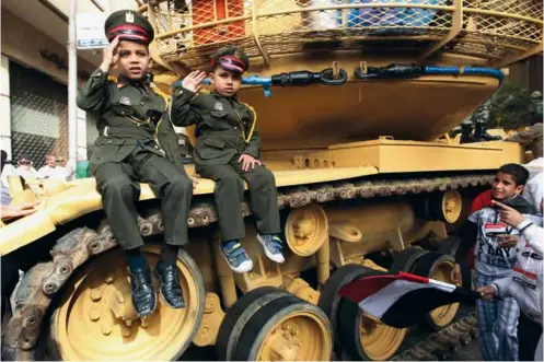  ??  ?? Deux garçons posent en uniforme sur un char, sur la place Tahrir du Caire, le 25 février 2011.