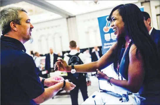  ?? PHOTOS BY SCOTT MCINTYRE / THE NEW YORK TIMES ?? Shane Eastridge and Jessica Stancil tap their Klik bracelets Sept. 6 at the THINK conference in Boca Raton, Fla. Technology is changing big corporate events at an accelerati­ng pace, offering innovative tools and less privacy.