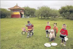  ??  ?? TIBETAN children play near a shrine in Aba built to honor Gonpo’s father. His people were fiercely independen­t; the king reported neither to the Tibetan government nor the Chinese.