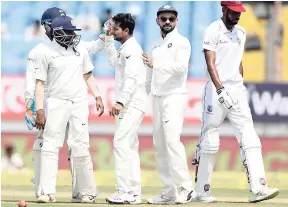  ??  ?? India’s Kuldeep Yadav (centre) celebrates with teammates after dismissing West Indies’ Roston Chase (right) during the third day of the first Test in Rajkot, India.