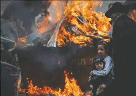  ?? (AP/Oded Balilty) ?? Ultra-Orthodox Jewish men and children burn leavened items in final preparatio­n for the Passover holiday in the ultra-Orthodox Jewish town of Bnei Brak, near Tel Aviv, Israel. Jews are forbidden to eat leavened foodstuffs during the Passover holiday that celebrates the biblical story of the Israelites’ escape from slavery and exodus from Egypt.