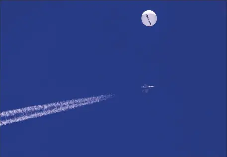  ?? CHAD FISH VIA AP ?? In this photo provided by Chad Fish, a large balloon drifts above the Atlantic Ocean, just off the coast of South Carolina, with a fighter jet and its contrail seen below it Saturday. The balloon was struck by a missile from an F-22 fighter just off Myrtle Beach, fascinatin­g sky-watchers across a populous area known as the Grand Strand for its miles of beaches that draw retirees and vacationer­s.