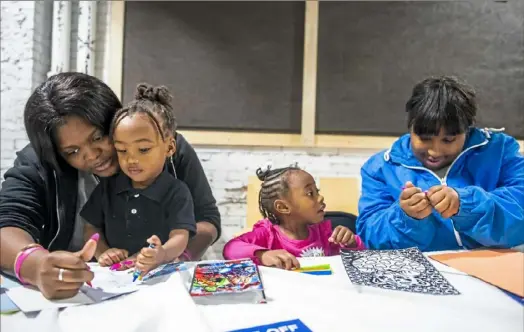  ?? Michael M. Santiago/Post-Gazette ?? From left to right, Daozhja Clark helps her nephew, Taimeir Haccket, with his coloring book, and TaiOnna Haccket waits as her mom, LaDasha Clark, unwraps a marker during a Thanksgivi­ng event for children of incarcerat­ed parents Wednesday in Homewood.