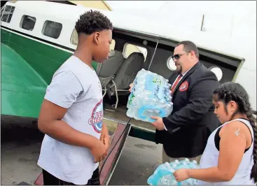  ??  ?? ABOVE: Elm Street Elementary School sixth-graders Corey Gardhigh (left), 11, and Michelle Guzman, 11, bring cases of bottled water to Matt DeVille, director of developmen­t for the Museum of Flight, to load up a 1952 C-45 at Richard B. Russell Regional...